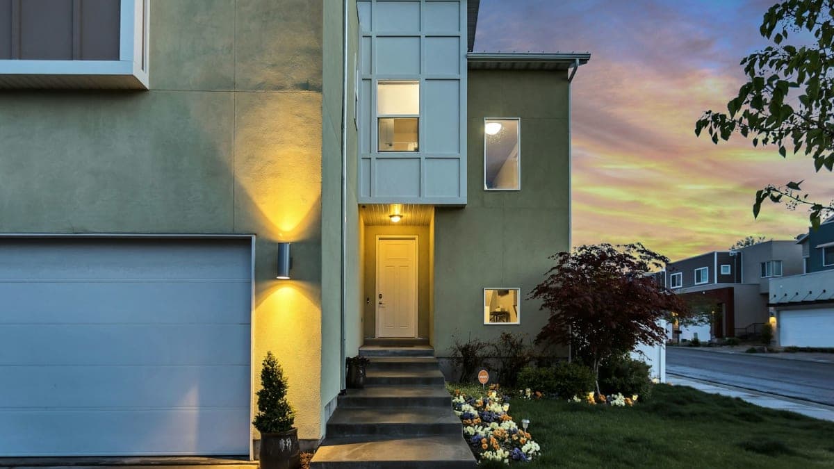 Two-story rental home with a lit front entry at dusk